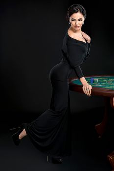 Full length portrait of sexy woman with poker cards and chips. Female player in a beautiful black dress.