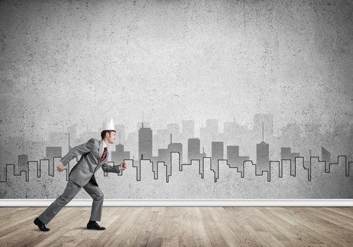 Young handsome businessman wearing white paper crown running in a hurry