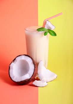 Pina Colada - Tropical Cocktail with Pineapple Juice, Coconut Milk and Rum. Fresh Summer Drink with Cracked Coconut and Mint on Coral and Yellow Background. Copy Space For Your Text.