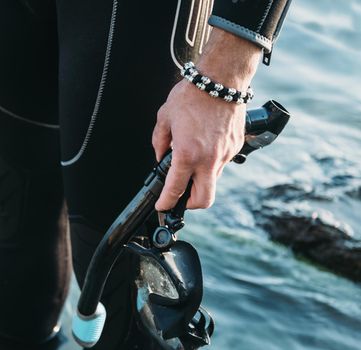 Close-up of diver male hand with snorkel mask on background of sea