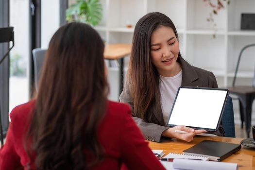 Group of young business people brainstorming at a meeting starting a new business with blank white screen tablet.