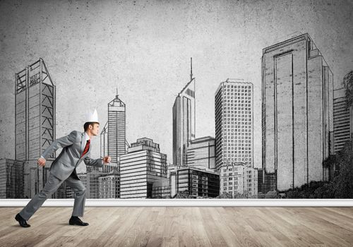 Young handsome businessman wearing white paper crown running in a hurry