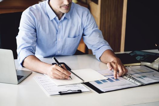 financial budget audit A male auditor is using a pen to write down budgets to trace the company's financial fraud