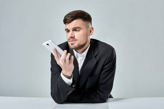 Handsome young man talking on the mobile phone while sitting at his working place in office. Emotions