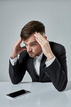 Portrait of attractive young caucasian man using cellular phone while sitting at office table. emotions