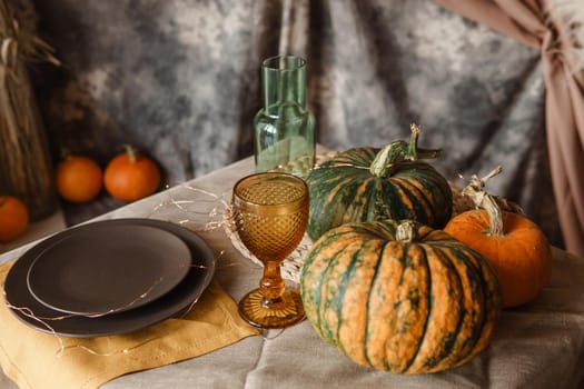 Autumn interior: a table covered with dishes, pumpkins, a relaxed composition of Japanese pampas grass. Interior in the photo Studio. Close - up of a decorated autumn table.