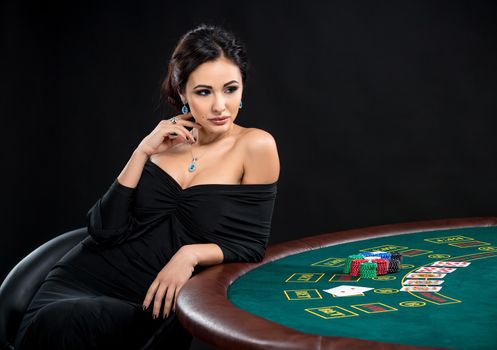 sexy woman with poker cards and chips. Female player in a beautiful black dress. girl sitting at the poker table