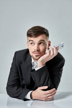 Handsome young man talking on the mobile phone while sitting at his working place in office. Emotions