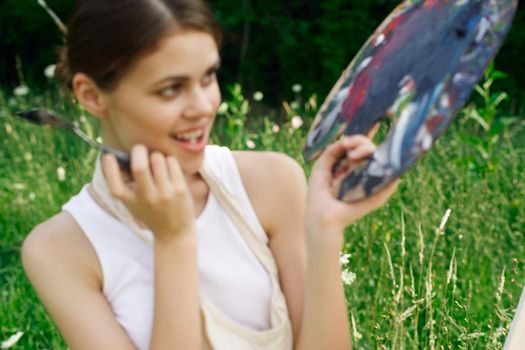 cheerful woman paints a picture palette nature landscape. High quality photo