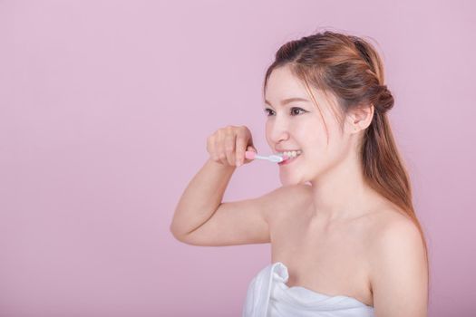 happy beautiful woman brushing her teeth on pink background