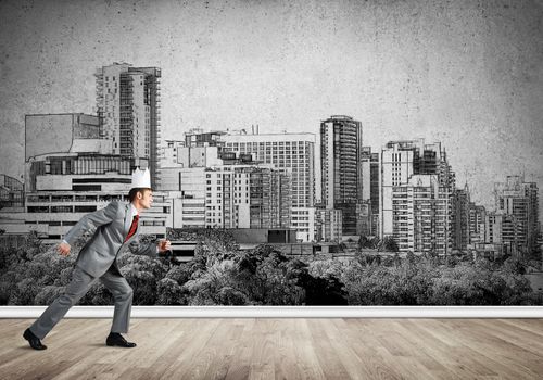 Young handsome businessman wearing white paper crown running in a hurry