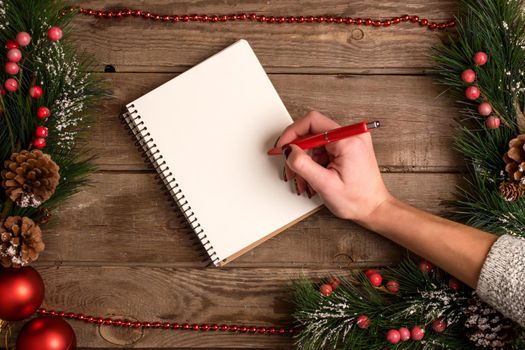 New Year and Christmas mokcup. hand writing on a notebook with Xmas lights on wooden background, space for your text, copyspace. from above. Holiday winter planning concept. Flat lay style.