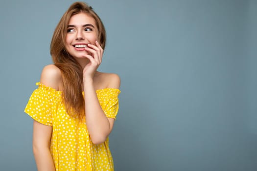 Shot of attractive happy smiling young woman wearing casual outfit standing isolated over colourful background with empty space looking to the side.