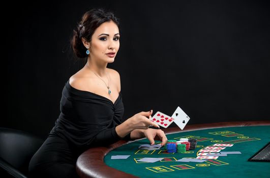sexy woman with poker cards. Female player in a beautiful black dress. girl sitting at the poker table and throws a cards