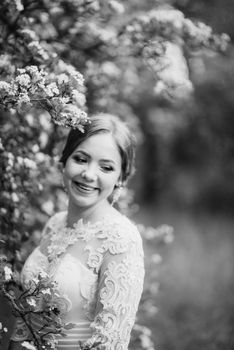 bride with a wedding bouquet in the forest near the bushes blooming with white flowers