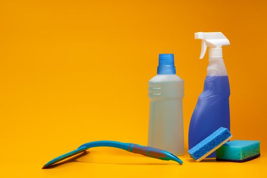 House cleaning detergent bottles on a yellow background, copy space