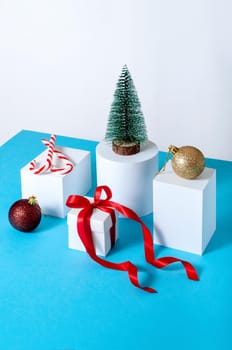 Creative Minimal Christmas Concept with Fir Tree, Gift Box, Ball and Candys on Different Geometrics Podium.