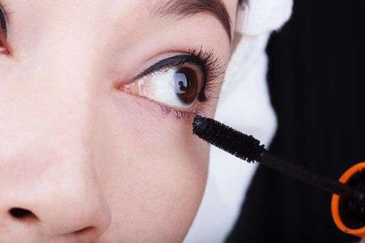 close-up woman applying mascara on her eyelashes