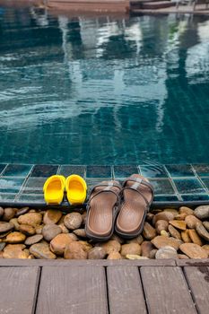 Concept of rest with a child at sea. Slippers stand by the edge pool against the background of ripples of water and nobody