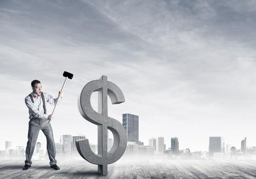 Young furious businessman going to crash with hammer stone dollar symbol