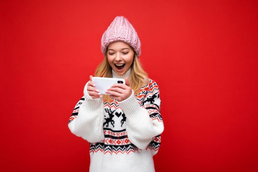 Photo of attractive crazy amazed surprised young woman wearing casual stylish clothes standing isolated over background with copy space holding and using mobile phone looking at screen display.