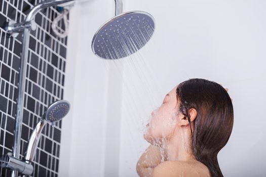 Woman is washing her face by rain shower head