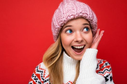 Closeup photo of beautiful happy surprised young blonde woman standing isolated over colourful background wall wearing everyday trendy clothes looking to the side showing facial emotions.