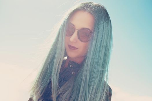 Portrait of dark style girl in round sunglasses with blue hair outdoor