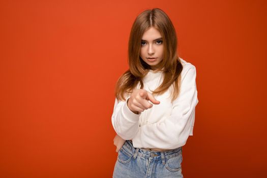 Portrait of beautiful sad upset sorrowful young brunette woman wearing knitted jersey isolated over red background with copy space and touching short brown hair and having split ends.