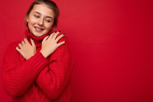 Cute young beautiful brunette female person with sincere emotions isolated on background wall with copy space wearing stylish red sweater. Positive concept.