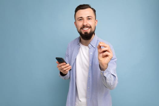 a young man with a beard on the background of a blue wall shows a gesture delicious.