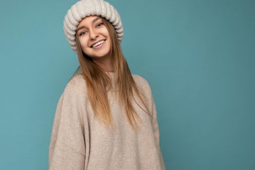 Attractive smiling happy young dark blond woman standing isolated over colorful background wall wearing everyday stylish outfit showing facial emotions looking at camera. Empty space
