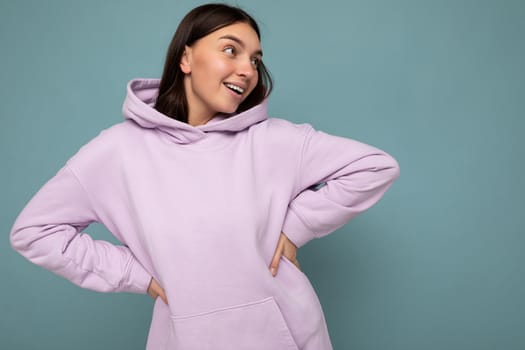 Shot of attractive happy smiling young woman wearing casual outfit standing isolated over colourful background with empty space looking to the side.