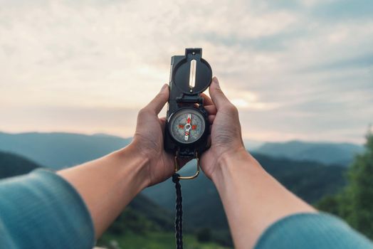 Traveler young woman searching direction with a compass in summer mountains. Point of view shot