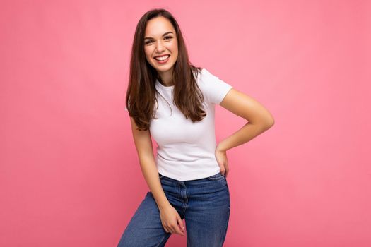 Portrait of positive cheerful fashionable woman in casual t-shirt for mock up isolated on pink background with copy space.