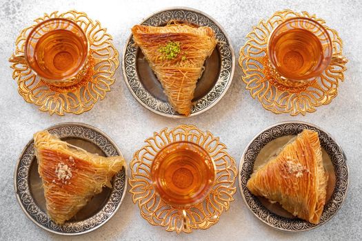 Turkish baklava and Turkish tea in oriental dishes on gray background, close up