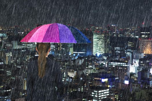 business woman holding multicolored umbrella with falling rain at tokyo city background, Japan