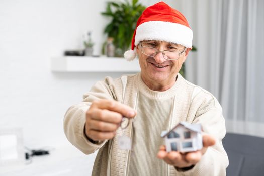 Portrait of elderly man in santa hat hold key small house