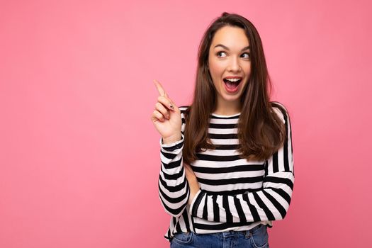 Shot of young positive happy surprised nice cute brunette woman with sincere emotions wearing casual striped sweater isolated on pink background with empty space and having an idea.