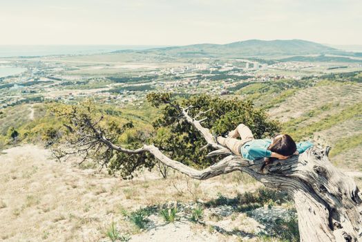 Young woman lying on tree and enjoying a nature