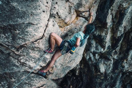 Young woman in safety harness with outfit coating her hand in chalk magnesium on the rock wall outdoor