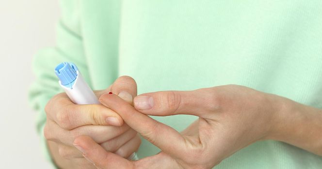 Woman self-testing for diabetes. Girls diabetic puncture finger to measure blood