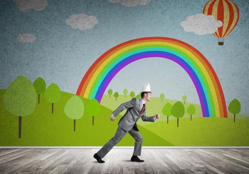 Young handsome businessman wearing white paper crown running in a hurry