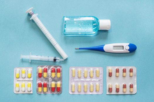 Virus prevention and treatment: wearing masks, hand disinfection, taking antiviral drugs and vitamins. First aid kit with medicines on a blue background.