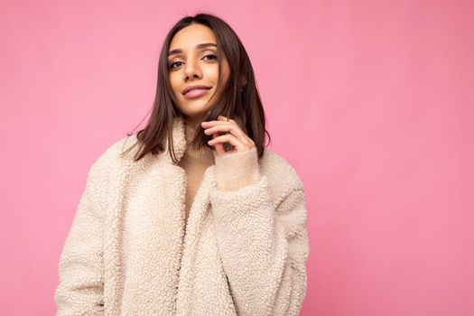 Portrait of attractive self-confident positive happy good-looking stylish young brunette woman wearing autumn beaige warm coat isolated on pink background with free space. Fashion concept.