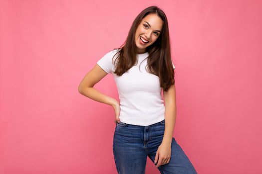 Portrait of positive cheerful fashionable woman in casual t-shirt for mock up isolated on pink background with copy space.