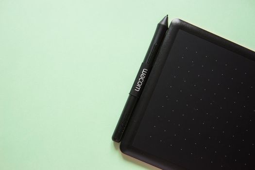 Tver, Russia - February 3, 2020 Top view of Wacom graphic tablet on pastel green background. Space for text. Selective focus.