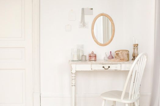 White colored vintage table and chair and mirror hanging on the wall in room