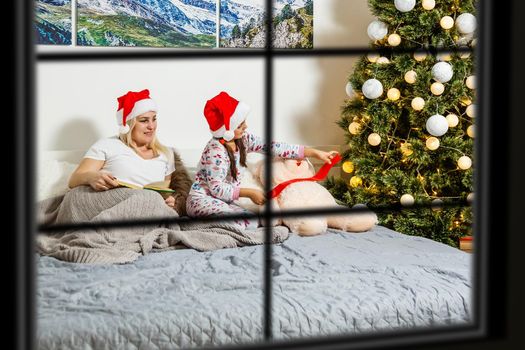 Big family with three children celebrating Christmas at home. Festive dinner at fireplace and Xmas tree. Parent and kids eating at fire place in decorated room. Child lighting advent wreath candle