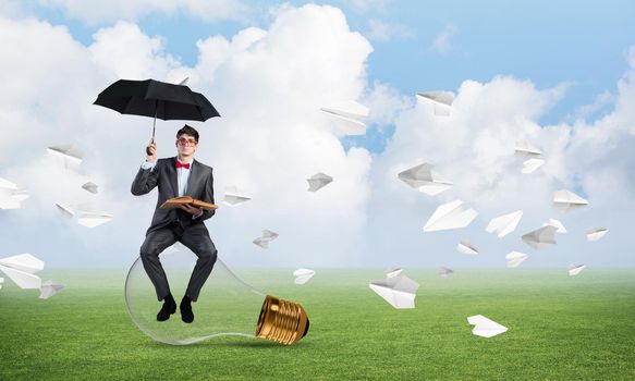 young businessman with umbrella and book, around fly in chaos paper plane